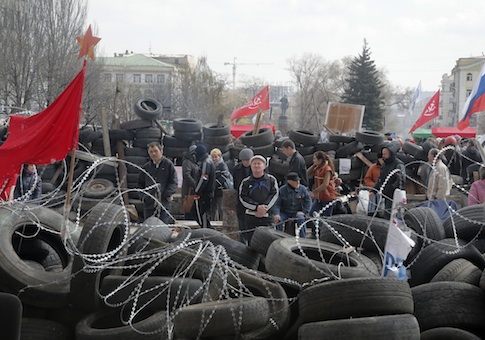People stand at a barricade at the regional administration building that they had seized earlier in Donetsk