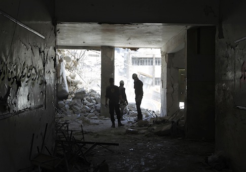 Rescuers watch an excavator operating at Ain Jalout school that was hit by what activists said was an airstrike by forces loyal to Syria's President Bashar al-Assad in Aleppo's al-Ansari al-Sharqi neighbourhood