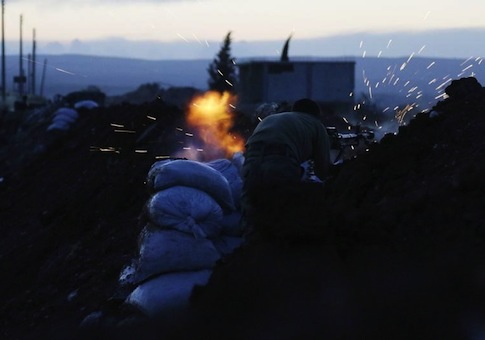 A rebel fighter takes a position as he fires his weapon towards forces loyal to Syria's President Assad who are stationed in Wadi al-Deif military camp in Idlib province