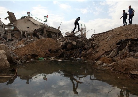 Palestinian students walking next to destroyed houses in Al-Shejaeiya neighbourhood in the east of Gaza City