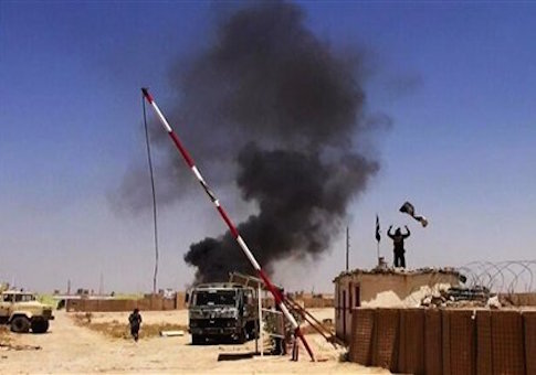 Militants raising the Islamic State flag at the entrance of an army base in Ninevah Province, Iraq