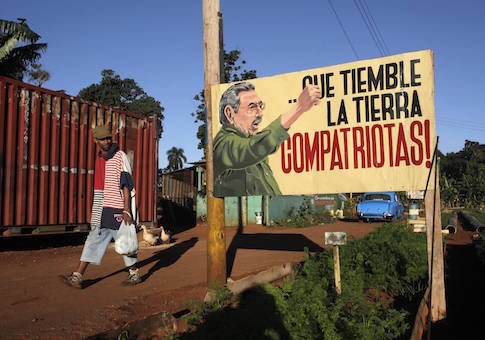 A man walks near a sign with an image of Cuban President Raul Castro in Havana December 19, 2014