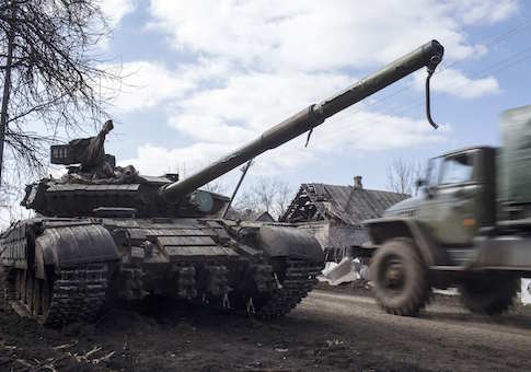 A truck passes by a pro-Russian rebel's tank with a gas mask placed on it's barrel in the village of Molochnoye, north-east from Donetsk