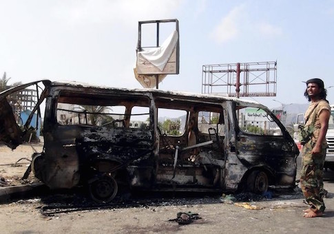 Man stands by the wreckage of a van hit by an air strike in Yemen's southern port city of Aden