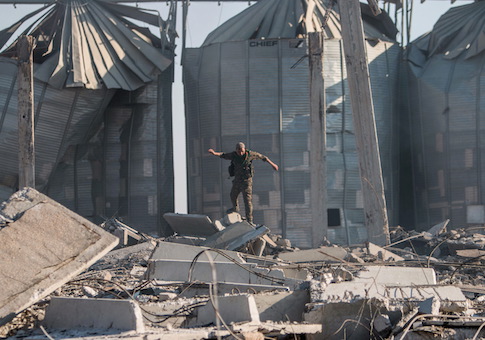 A YPG fighter walks amid debris around damaged silos of Aliya village after saying that they retook control of the area from IS in the southern countryside of Ras al-Ain