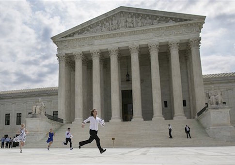 Members of the news media, including interns for network television stations, run with decisions in hand on the opinion for health care outside of the Supreme Court in Washington