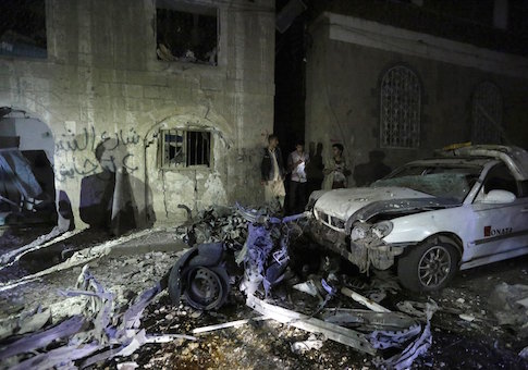 People stand next to wreckage at the site of a car bomb attack in Yemen's capital Sanaa