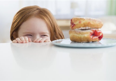 Caucasian girl peeking at donuts on table