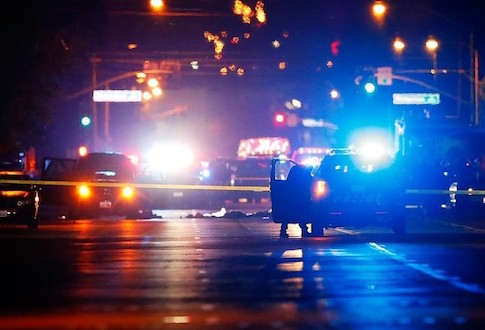 Police vehicles line the street around a vehicle in which two suspects were shot following a mass shooting in San Bernardino