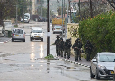 Israeli soldiers walk in line in the village of Arara