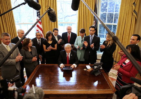 U.S. President Donald Trump signs an executive order cutting regulations, accompanied by small business leaders at the Oval Office of the White House in Washington U.S.