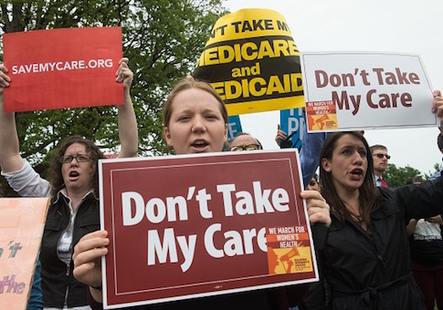 Protesters hold signs and shout at lawmakers walking out of the US Capitol after the House of Representatives narrowly passed a Republican effort to repeal and replace Obamacare