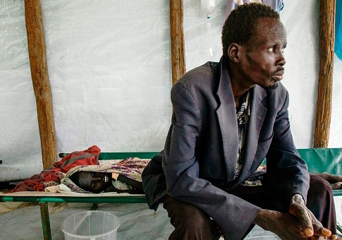 A man in South Sudan sits next to his son stricken with Cholera / Getty Images