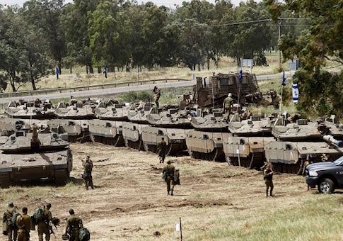 Israeli soldiers walk by tanks during a military drill in the Golan Heights