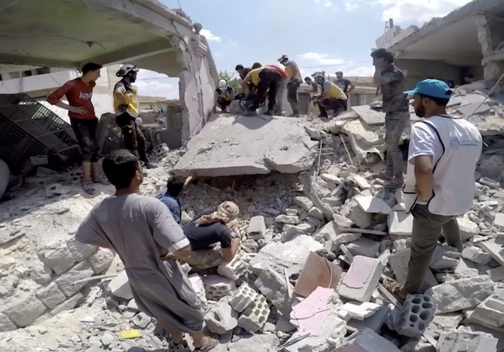A White Helmets member uses a saw on rubble after an airstrike
