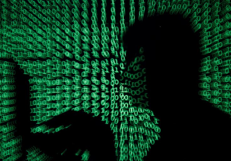 FILE PHOTO: Man holds laptop computer as cyber code is projected on him in this illustration picture