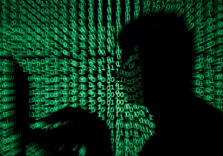 FILE PHOTO: Man holds laptop computer as cyber code is projected on him in this illustration picture