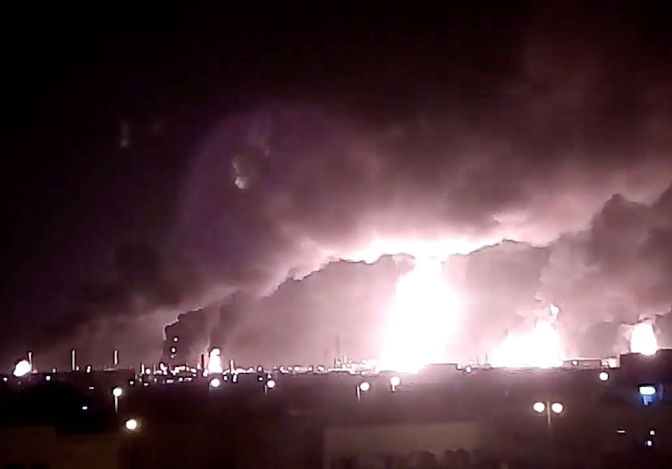 Fires burn in the distance after a drone strike by Yemen's Iran-aligned Houthi group on Saudi company Aramco's oil processing facilities, in Buqayq, Saudi Arabia